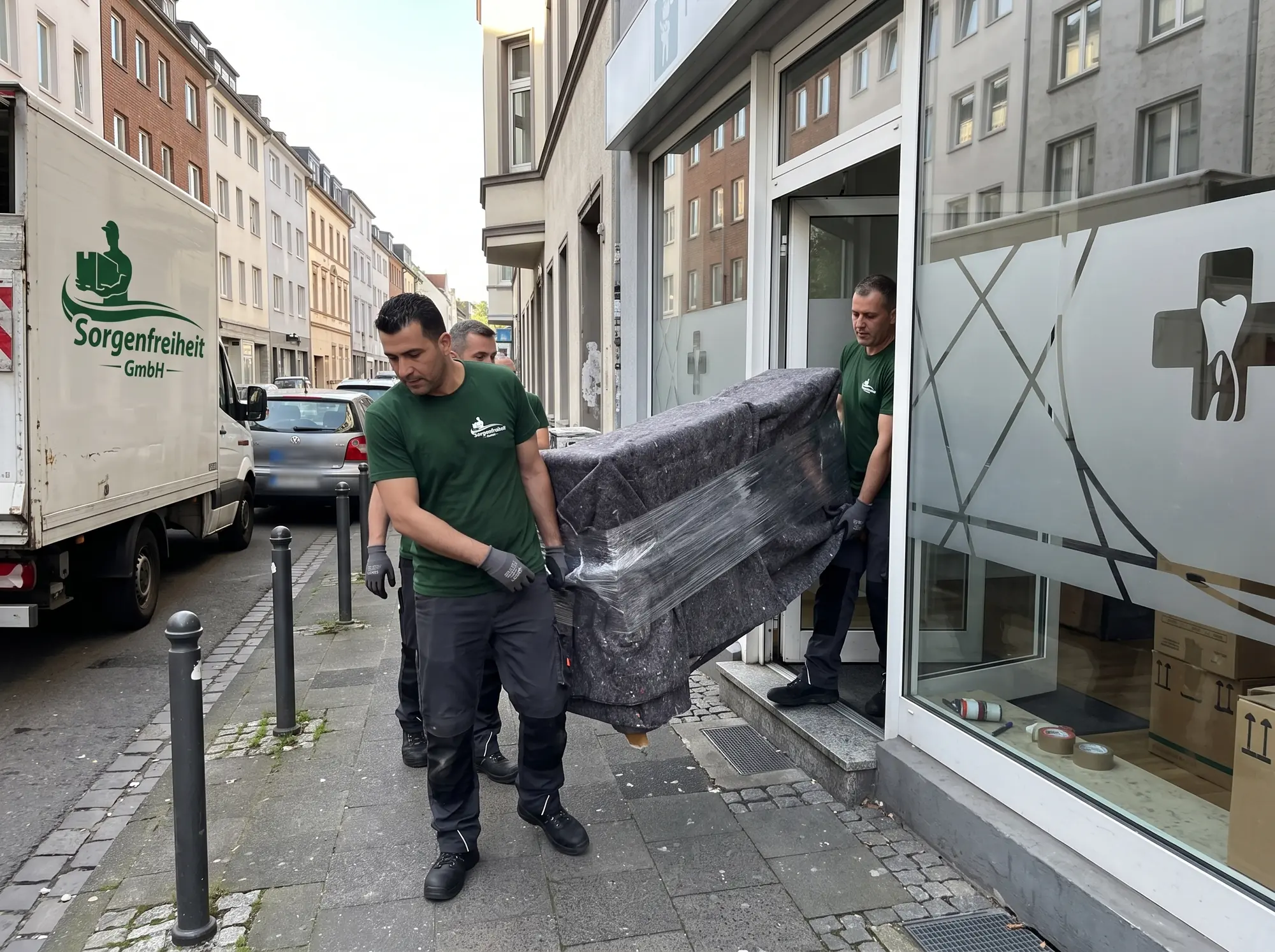 Gewerbeumzug: Umzugshelfer der Sorgenfreiheit GmbH tragen eine verpackte Empfangstheke aus einem Ladenlokal